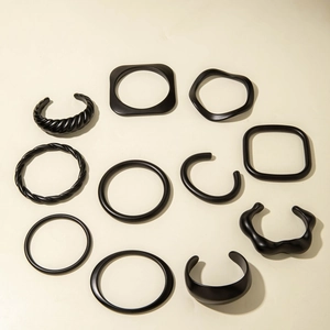 Collection of matte black acrylic bracelets with geometric designs and twisted patterns