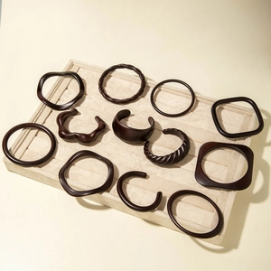Macro display of twelve assorted dark brown acrylic resin bracelets in geometric shapes
