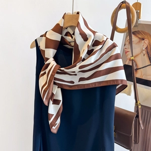 Brown zebra striped silk scarf tied on a hanger with summer sleeveless dress