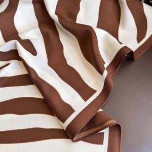 Detail of coffee and white striped silk scarf showing twill texture and rolled edge
