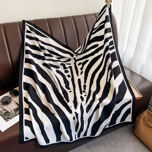 Detail of zebra pattern silk scarf on leather sofa with luxury lifestyle accessories
