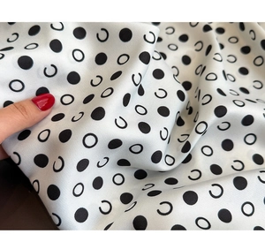 Detail eines weichen schwarz-weißen Polka-Dot-Seidenschals mit glänzendem Finish und Falten
