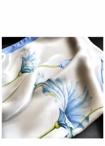 Close-up of smooth satin silk scarf featuring elegant blue floral print and fine stitching
