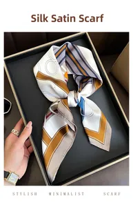 Close-up of a satin silk square scarf with geometric chain prints on a display tray