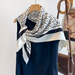 Nahaufnahme von schwarz-weißem Seidenschal mit geometrischem Muster auf blauem Kleid