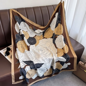 Detail of elegant satin square scarf with vintage floral patterns on a leather sofa