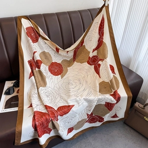 Detail of silk-like square scarf with red rose floral prints on a leather surface