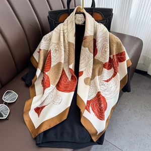 Vintage camellia print silk square scarf on luxury leather background with sunglasses