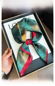 Dettaglio del foulard in seta floreale verde scuro annodato su un vassoio elegante