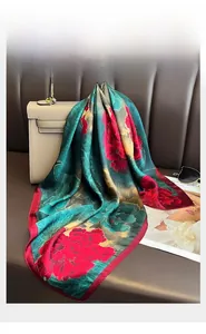 Vista dettagliata di un foulard di seta verde scuro con peonie rosse su una borsa