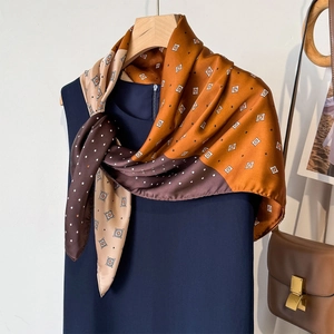 Elegant silk-texture printed square scarf with geometric patterns on a blue dress