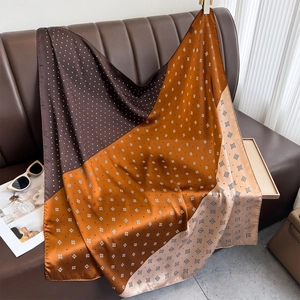 Elegant geometric patchwork silk scarf with dots and diamond patterns on a leather sofa
