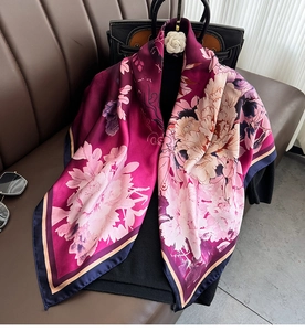 Detail of silk scarf with purple peony floral print draped over a black sweater