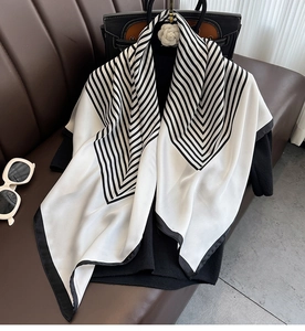 Close-up of elegant silk-textured square scarf with black and white stripes on leather