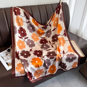 Elegant floral print square silk scarf with daisy patterns on a vintage leather sofa