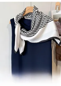 Detail view of a black and white striped silk scarf draped on a navy blue dress