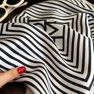Detail of silk-satin scarf showing smooth texture and elegant black-white stripe patterns