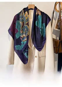 Detailed texture of silk-like floral scarf with lotus patterns against a white blazer