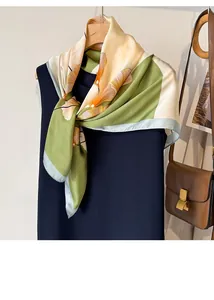 Dettaglio di un foulard in seta verde e beige con stampa ginkgo su abito blu