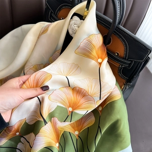 Elegante sciarpa in seta con stampa a foglie di ginkgo su una borsa scura in luce naturale