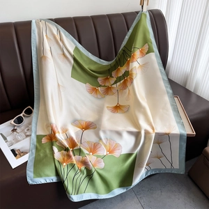 Elegante foulard in seta con stampa a foglie di ginkgo su divano in pelle