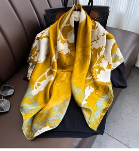 Detail of elegant ginger yellow silk scarf draped on a sofa with floral prints