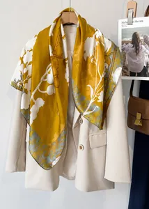 Detail of elegant silk-like square scarf with yellow floral print on a beige blazer