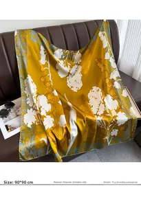 Detail of 90x90cm yellow faux silk scarf with white floral print on a leather sofa
