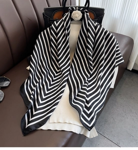 Detail of black and white striped satin silk scarf draped over a camellia hanger