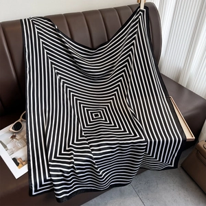 Chic black and white geometric striped satin square scarf draped on a leather sofa