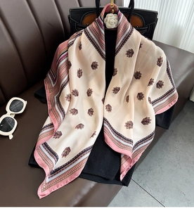 Close-up of lightweight silk scarf with purple leaf patterns on a beige background