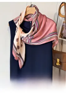 Close-up of lightweight printed silk-like scarf with floral patterns on a wooden hanger
