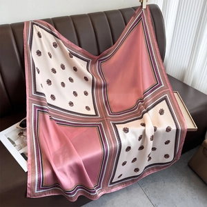 Elegant pink and cream faux silk square scarf with vintage leaf print on leather sofa