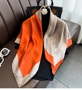 Detail of elegant orange and champagne satin silk scarf draped on a chic outfit