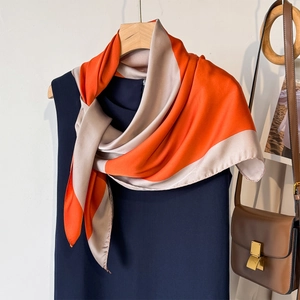 Elegant orange and beige color block silk scarf styled on a navy dress with a brown handbag