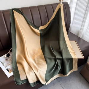 Detail of silk scarf with green and gold geometric patterns draped on a sofa