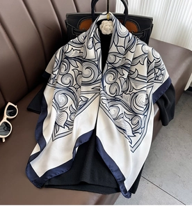 Close-up of elegant satin scarf with navy scroll print draped on a handbag