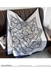 Close-up of 90x90cm satin silk square scarf with navy baroque floral pattern on leather sofa