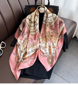 Close-up of pink baroque square scarf with gold chain patterns on a dark coat