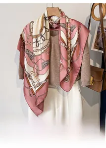 Detail view of pink satin square scarf with vintage chain patterns on beige sweater