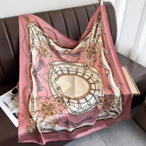 Satin square scarf with elegant equestrian chain print draped on a leather sofa