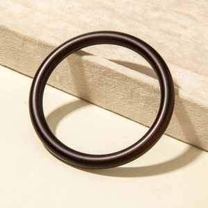 Close-up of polished dark brown acrylic resin bangle on a velvet display tray
