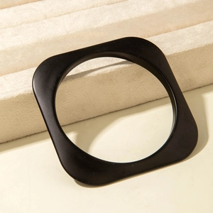 Close-up of minimalist black geometric acrylic bracelet with a matte finish on a stand
