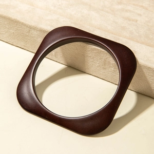 Detail of minimalist dark reddish-brown square acrylic bangle on a soft display stand