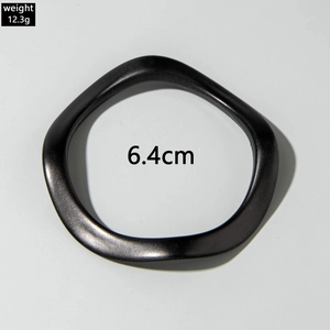 Detail view of a matte black wavy acrylic bangle with a 6.4cm diameter and 12.3g weight