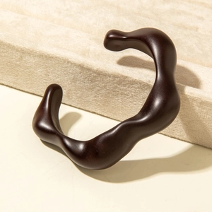 Detail of dark brown wavy acrylic bracelet with matte finish on velvet display