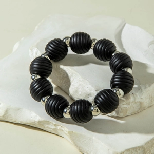 Close-up of matte black threaded beads and polished silver beads on a stone surface
