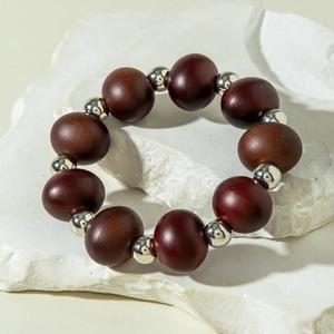 Close-up of beaded bracelet with dark brown beads and silver accents on white stone