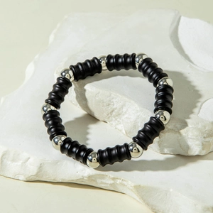 Detail of matte black threaded beads and polished silver beads on a minimalist elastic bracelet