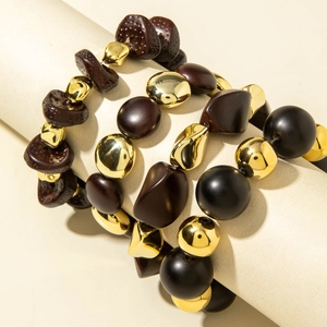Macro detail of three-piece beaded bracelet set with gold, black, and brown acrylic beads